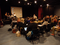 a lot of people sitting in a hall, on stage four women sitting in a row